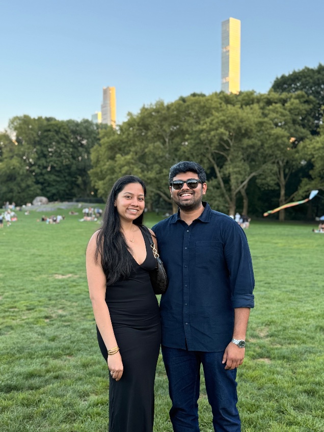 Dakshinya and Karthik standing together on the grass in Central Park with the Manhattan skyline behind them