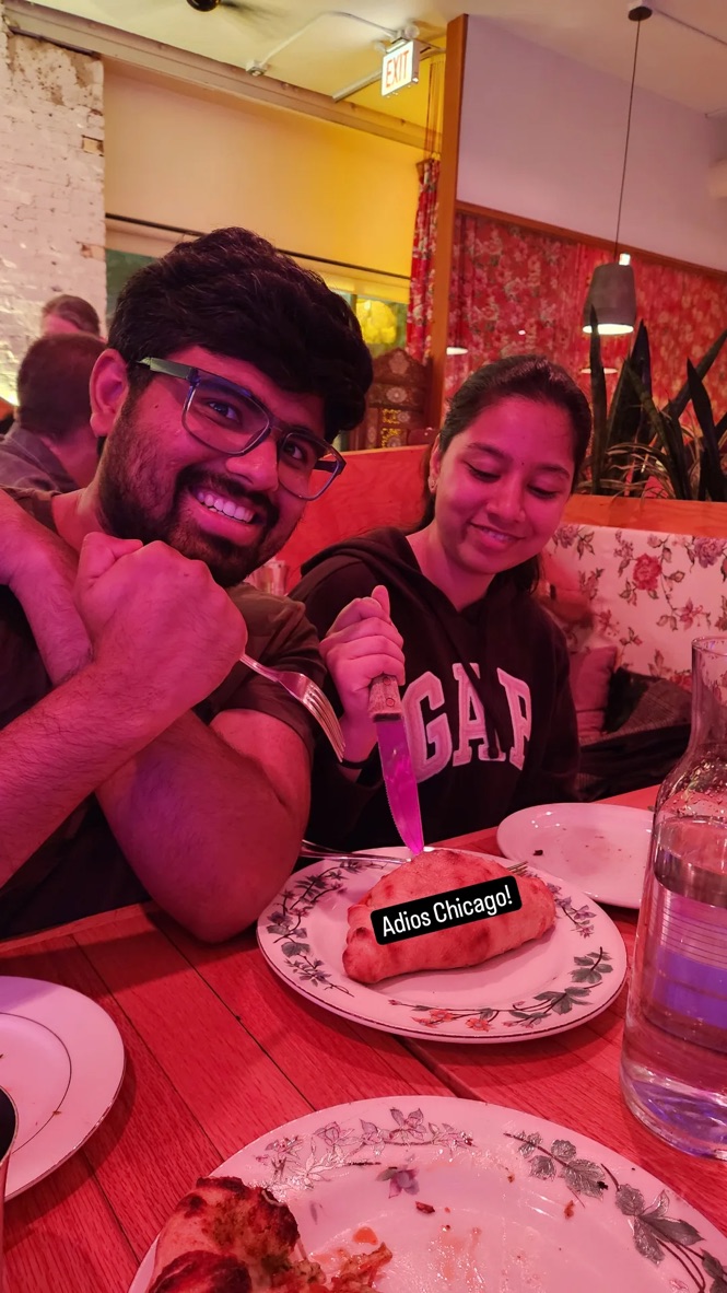 Dakshinya and Karthik at a restaurant table in Chicago, about to cut into a calzone