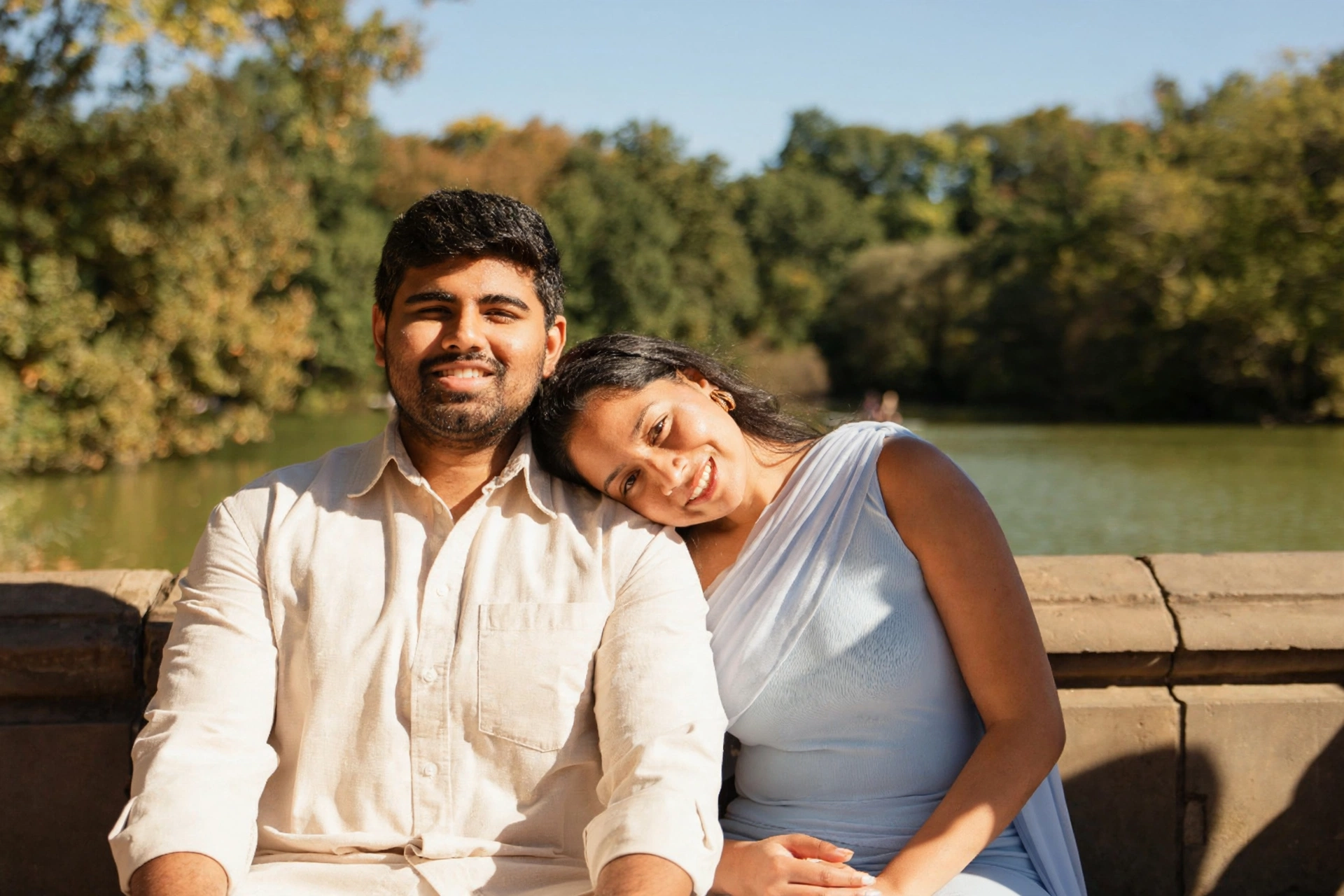 Dakshinya resting her head on Karthik's shoulder as they sit by the lake in the sunshine